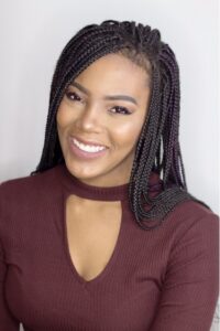 A woman with black braids smiling. 