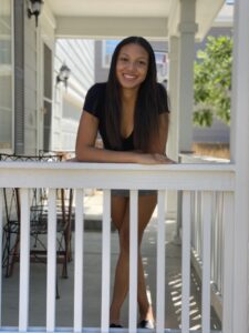 Girl with black hair leaning on a white rail smiling
