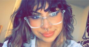 A woman with a septum piercing and clear glasses